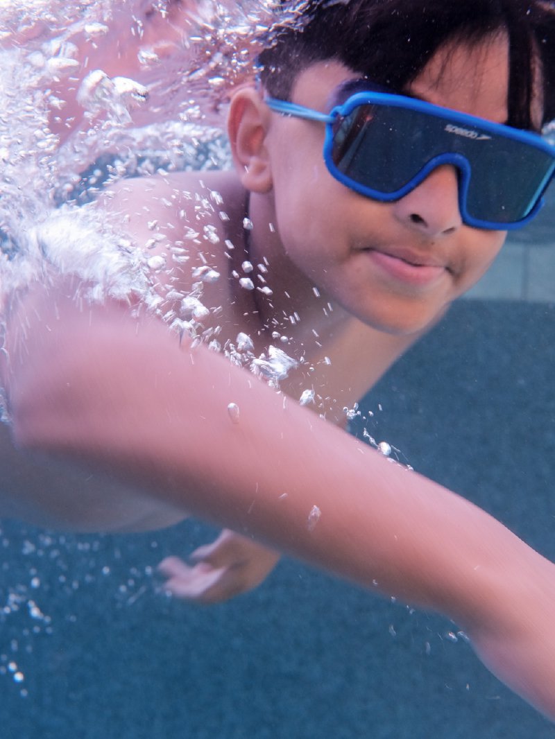 Underwater portrait of a boy in flag swim trunks during a Frisco pool session