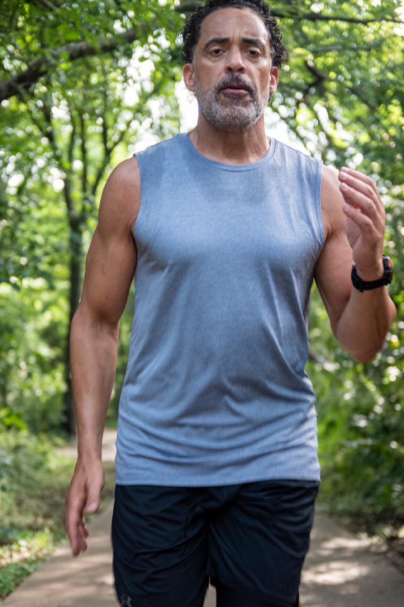 Athlete portrait of Corey mid-stride on a forest trail in Frisco