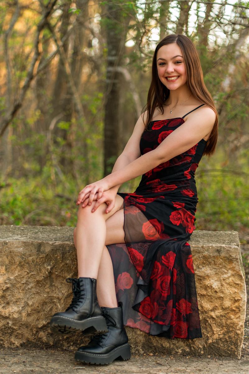 Senior portrait of Hailey in a well-fitted floral dress and boots at a Frisco park